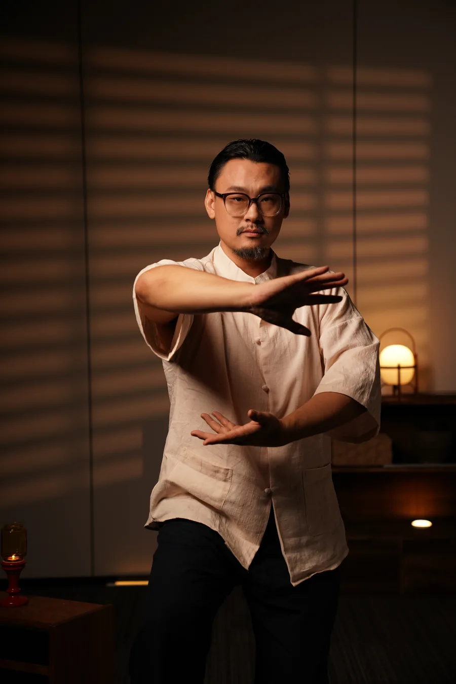 Master Lao standing in a taiji posture, weight settled, arms parting.