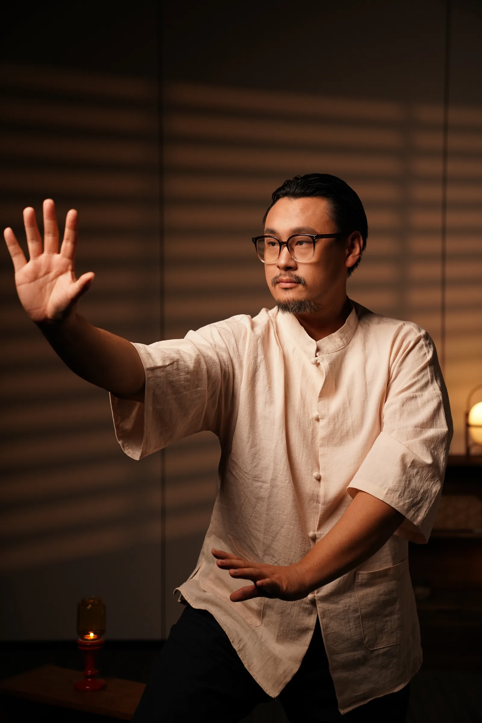 Master Lao mid-form, one palm extended, gaze following the hand.